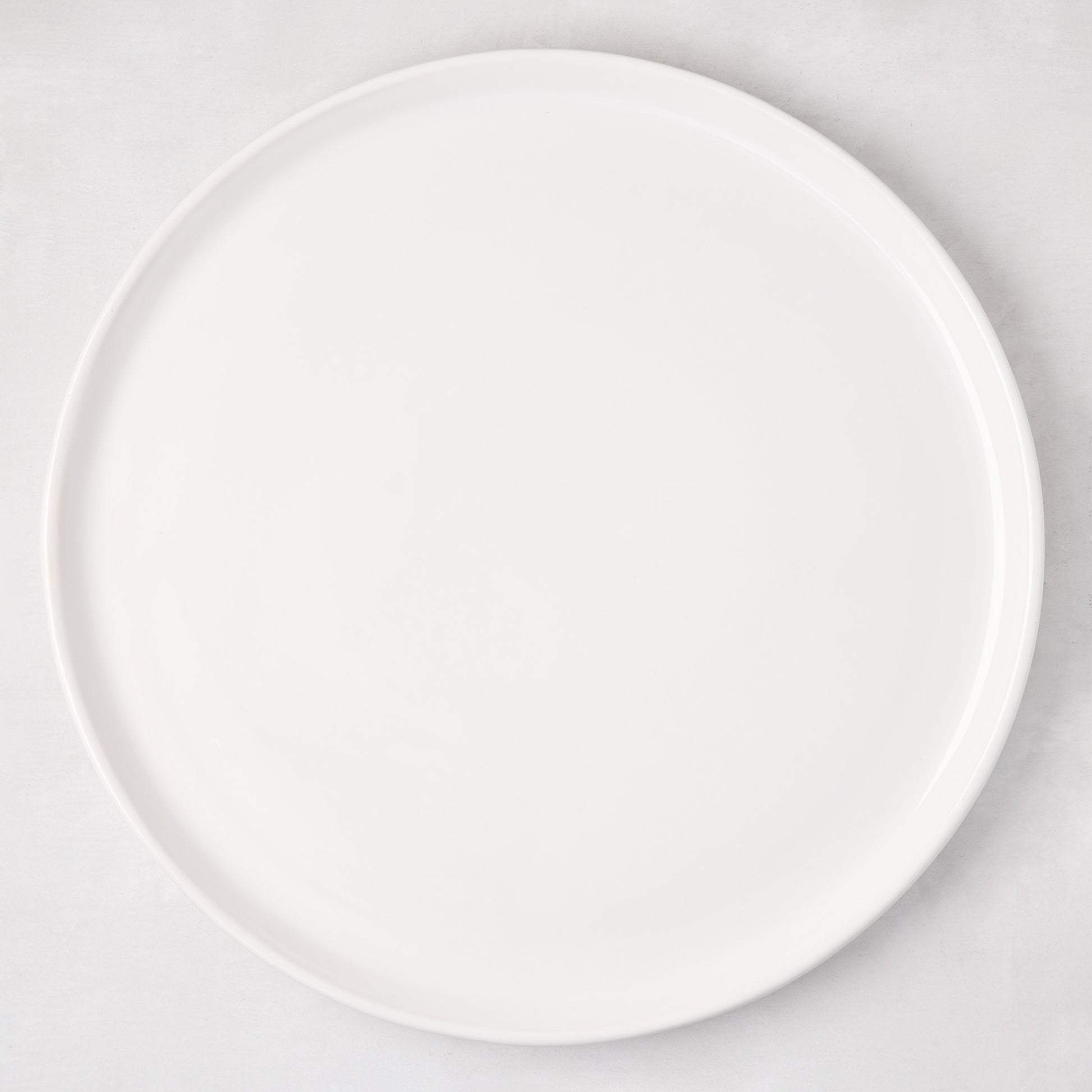 White ceramic round pizza serving platter, 12.6-inch diameter, with a subtle raised edge.