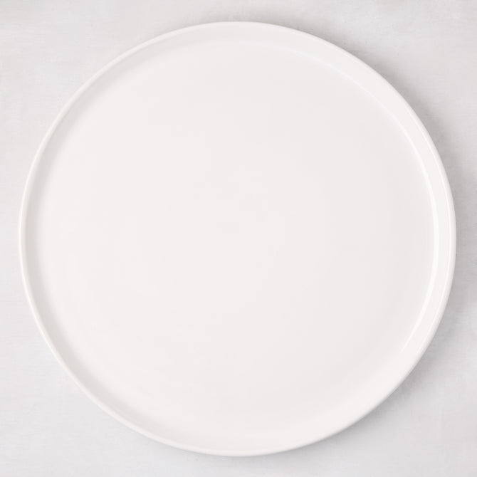 White ceramic round pizza serving platter, 12.6-inch diameter, with a subtle raised edge.