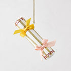 White Christmas cracker ornament with gold glitter stripes, red accents, and yellow and pink ribbon bows.