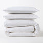 Stacked white Italian percale duvet set with two shams and a folded duvet cover.