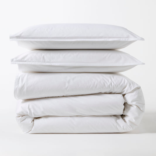 Stacked white Italian percale duvet set with two shams and a folded duvet cover.