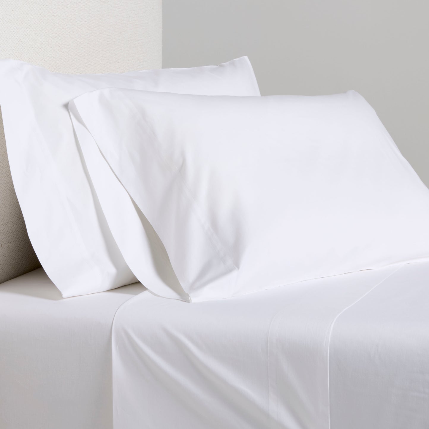 White Italian Percale Sheet Set with two pillowcases and flat sheet on a bed.