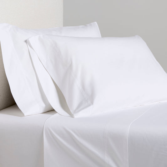 White Italian Percale Sheet Set with two pillowcases and flat sheet on a bed.