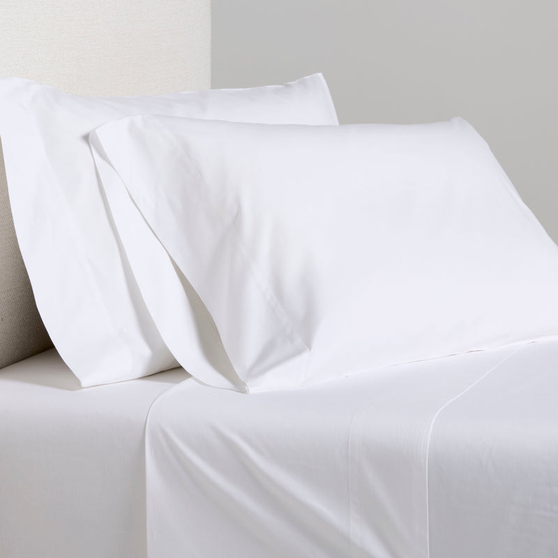 White Italian Percale Sheet Set with two pillowcases and flat sheet on a bed.