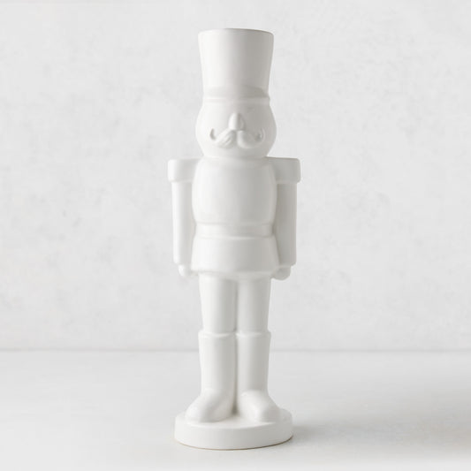Minimalist white ceramic nutcracker figurine with a smooth glossy finish and classic soldier uniform design.