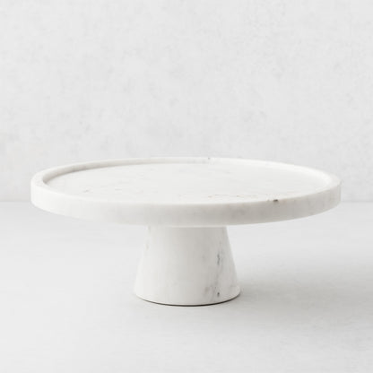 White marble cake stand, 12" diameter, with a raised lip and sturdy pedestal base.