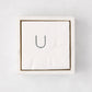 White marble square napkin holder with a stack of white napkins, top-down view.