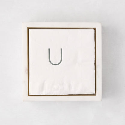 White marble square napkin holder with a stack of white napkins, top-down view.