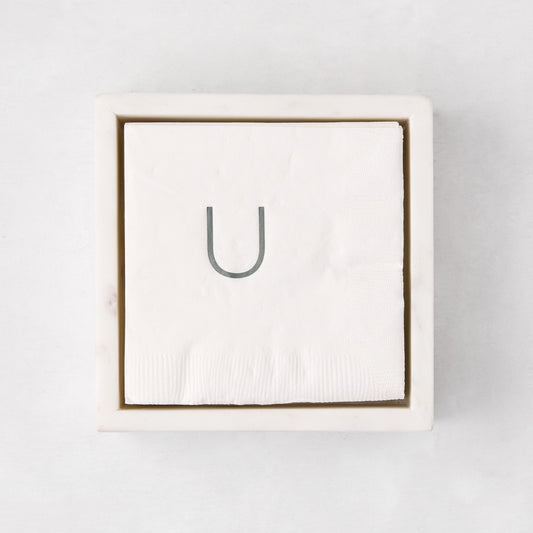 White marble square napkin holder with a stack of white napkins, top-down view.