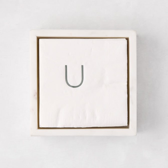 White marble square napkin holder with a stack of white napkins, top-down view.