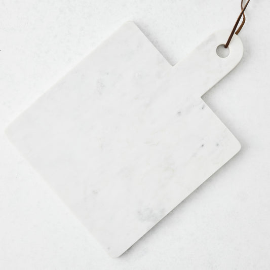 White marble square serve board with handle and brown leather strap.
