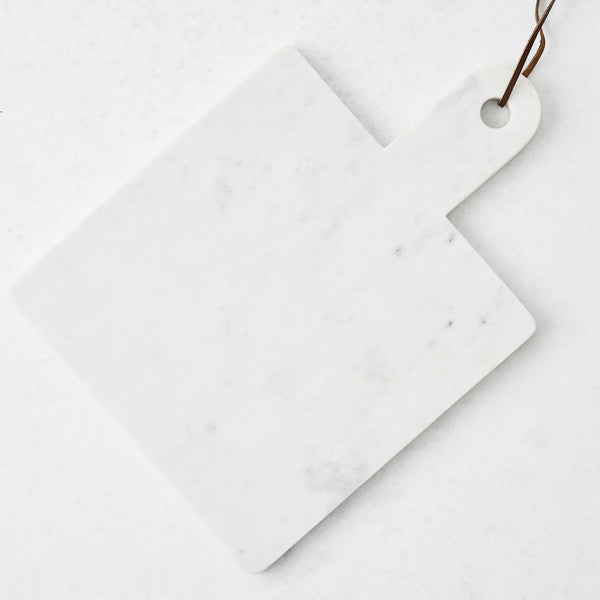 White marble square serve board with handle and brown leather strap.