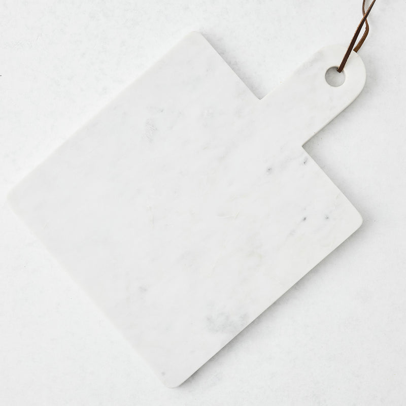 White marble square serve board with handle and brown leather strap.