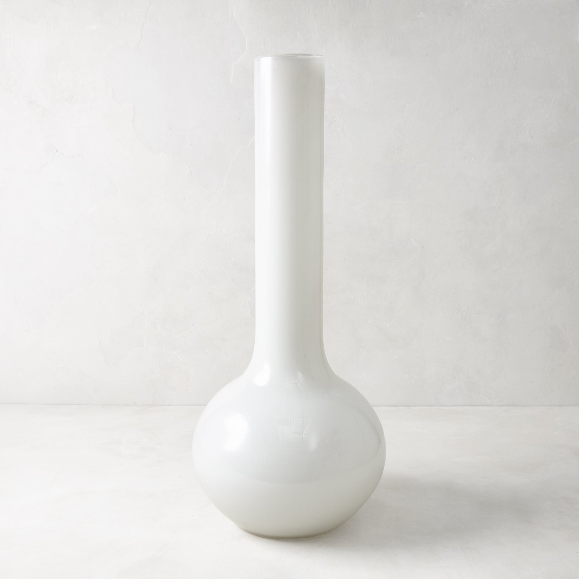 Oversized opaque white Raymond glass vase, handblown in Europe, with a round base and tall, slender neck.