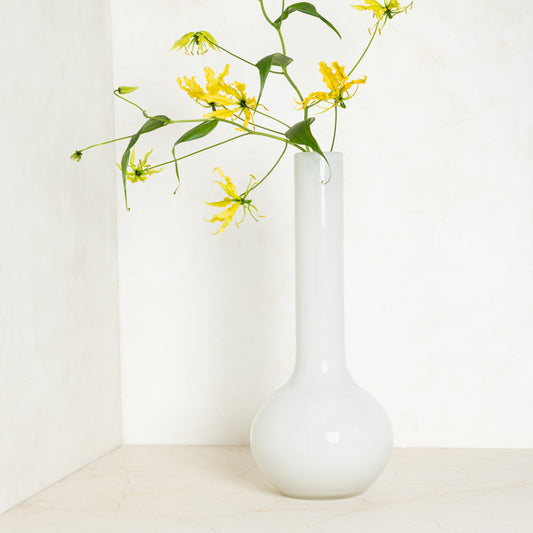 White oversized Raymond glass vase, handblown, with yellow flowers, 9.9”W x 23.6”H.