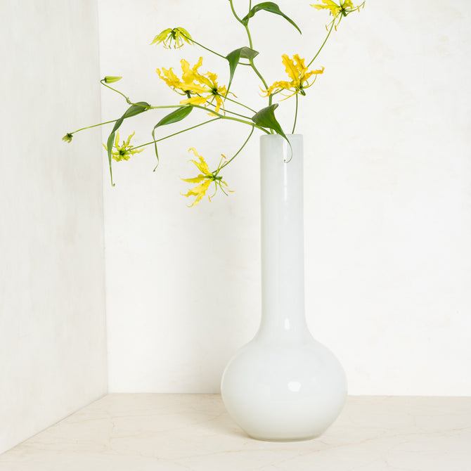 White oversized Raymond glass vase, handblown, with yellow flowers, 9.9”W x 23.6”H.