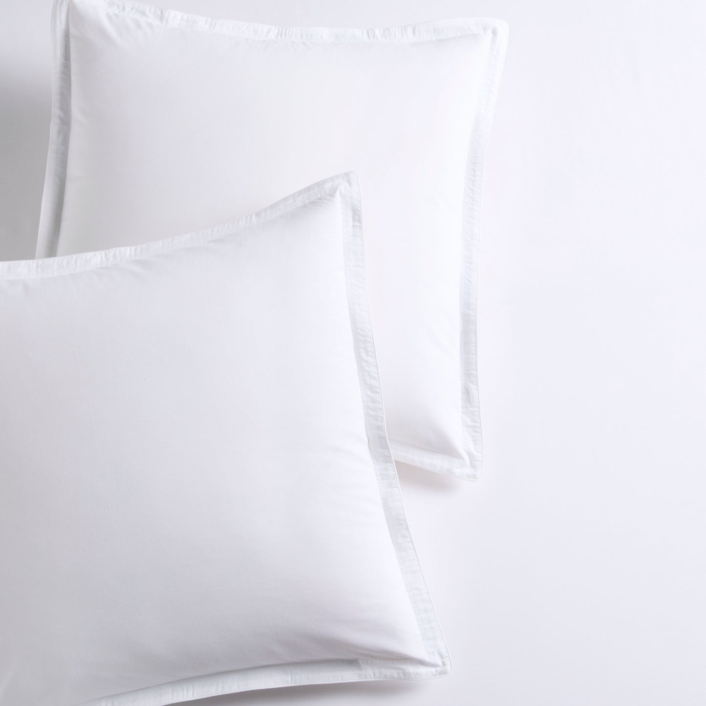 Set of 2 white piped percale Euro shams made from organic cotton.