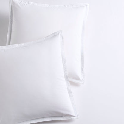 Set of 2 white piped percale Euro shams made from organic cotton.