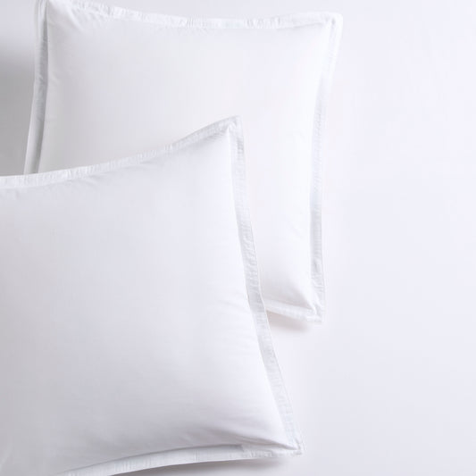 Set of 2 white piped percale Euro shams made from organic cotton.