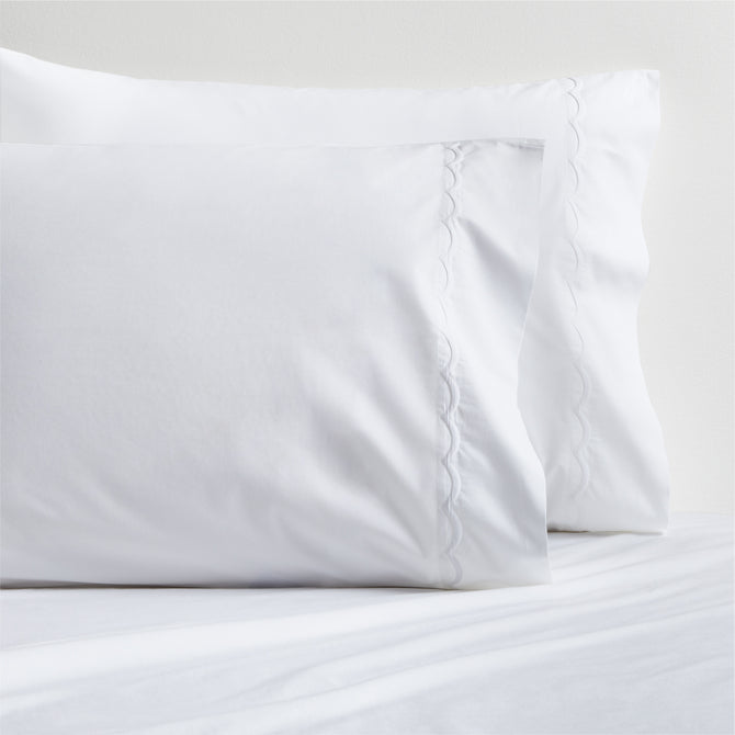 Set of 2 white percale pillowcases with delicate scallop stitch trim.
