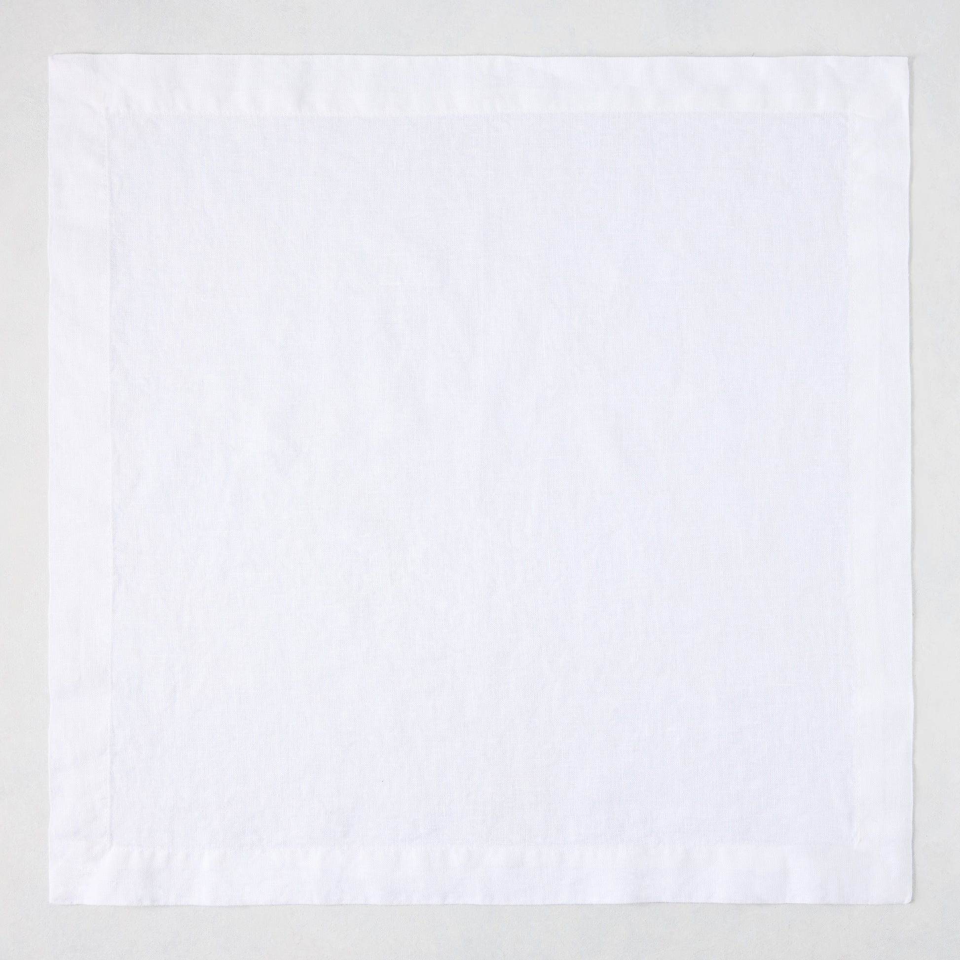 White HG Signature hand-dyed 22-inch square linen napkin with mitered corners.