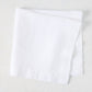White HG Signature hand-dyed 22" square linen napkin, folded on a light surface.