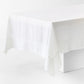 White hand-dyed 100% linen tablecloth with a wide border and mitered corner detailing draped over a table.