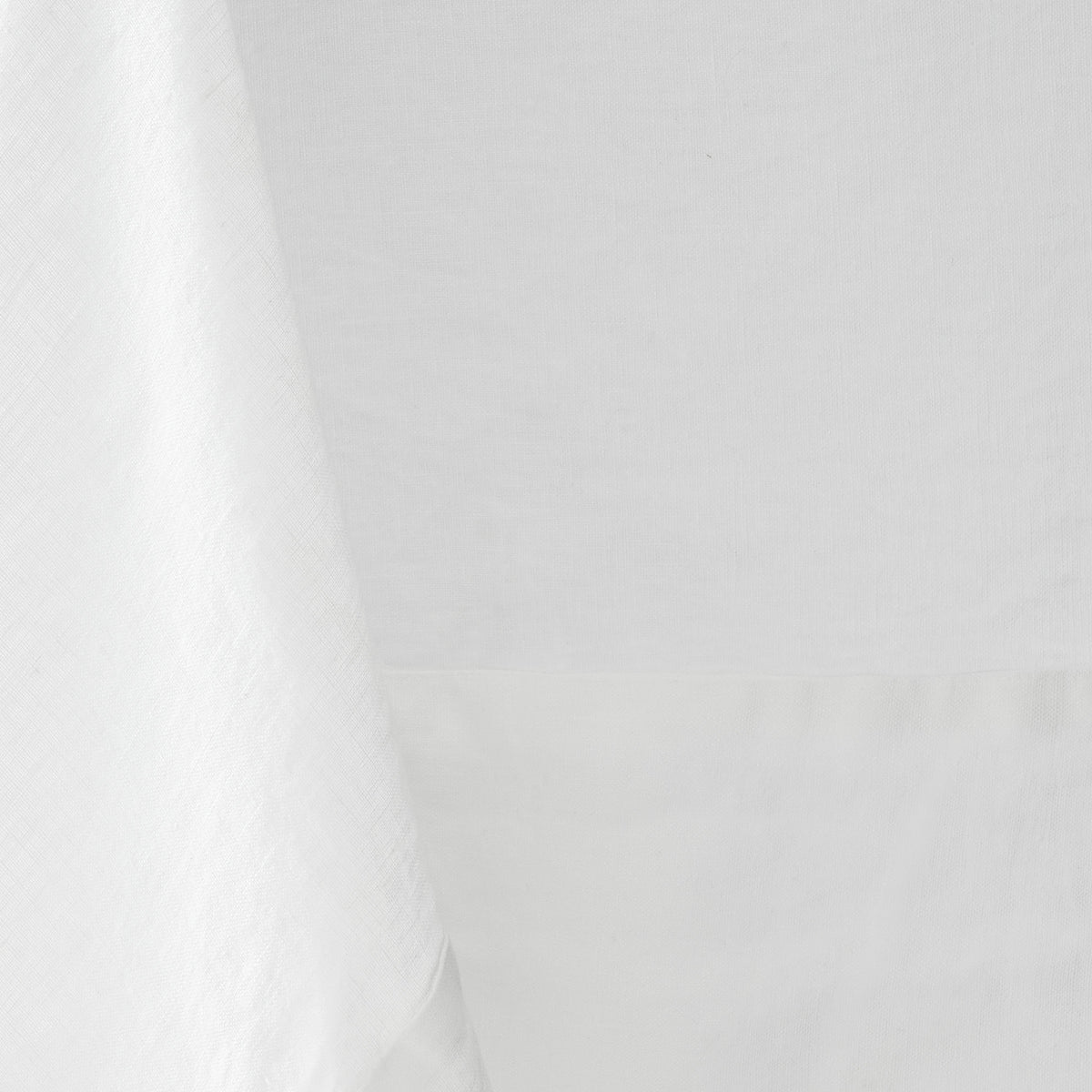 White hand-dyed 100% linen tablecloth with a soft texture and mitered corner detail.