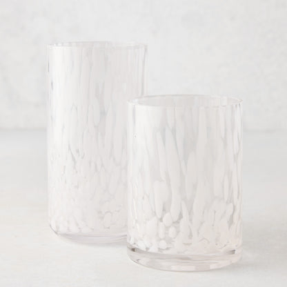 Two clear glass highball glasses with white spotted patterns, one taller than the other.