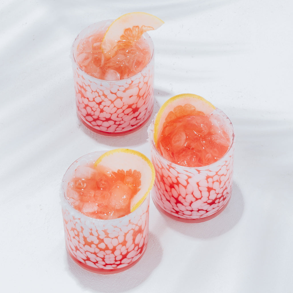 Three 15oz White Tortoise Double Old-Fashioned glasses with pink cocktails and grapefruit slices.