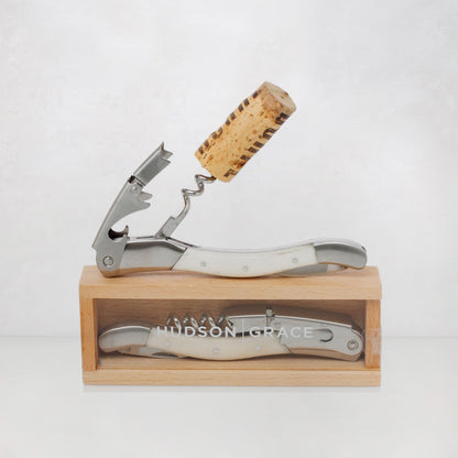 Hudson Grace white corkscrew with brushed stainless steel and bone-colored resin handle, shown open with a cork and closed in a wooden gift box.