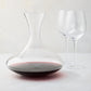 Mouth-blown glass wine carafe with broad base, curved neck, and red wine, paired with two clear HG Heritage wine glasses.