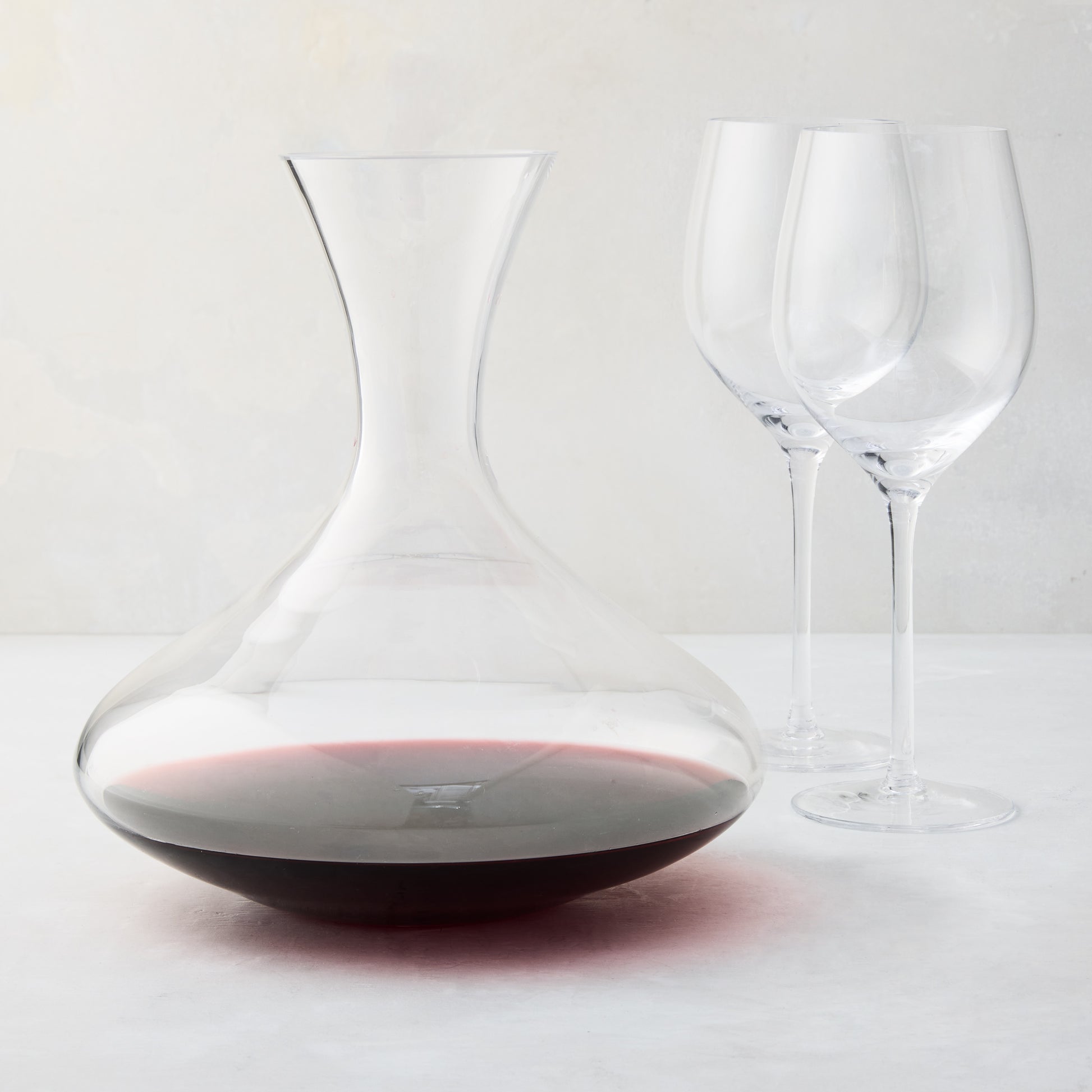 Mouth-blown glass wine carafe with broad base, curved neck, and red wine, paired with two clear HG Heritage wine glasses.