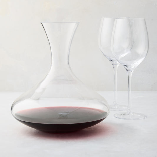 Mouth-blown glass wine carafe with broad base, curved neck, and red wine, paired with two clear HG Heritage wine glasses.
