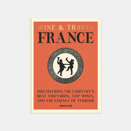 Hardcover "Wine & Travel France" book with orange cover, gold text, and a circular emblem of two figures.