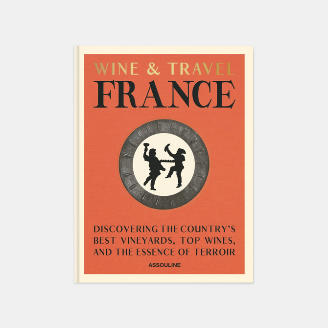 Hardcover "Wine & Travel France" book with orange cover, gold text, and a circular emblem of two figures.