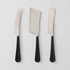 Three-piece cheese knife set with stainless steel blades and black, hand-forged, hammered metal handles.