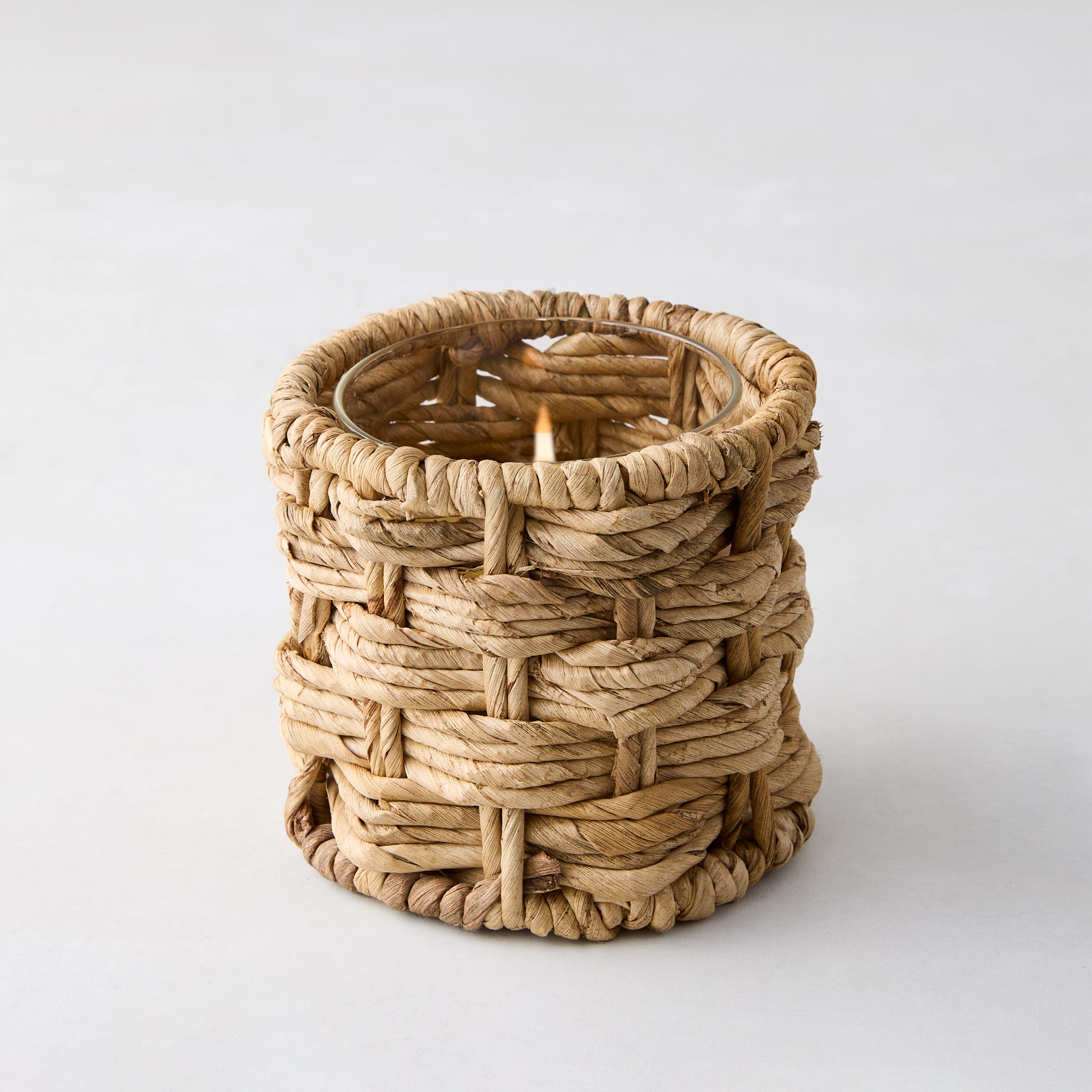 Woven banana bark votive candle holder with glass insert and lit tealight. Natural, textured, 4"Dia x 4"H.