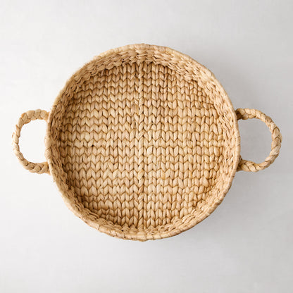 Round woven hyacinth tray with natural light brown fibers and two side handles, top-down view.