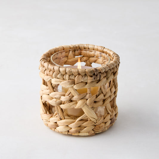 Woven hyacinth votive candle holder with a glass insert and lit candle, natural color, 4"Dia x 4"H.