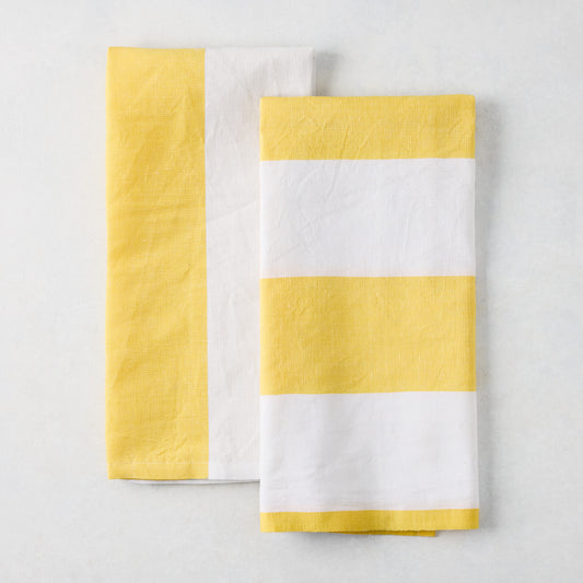 Set of 2 yellow and white block print cotton-linen hand towels; one striped, one half yellow/half white.