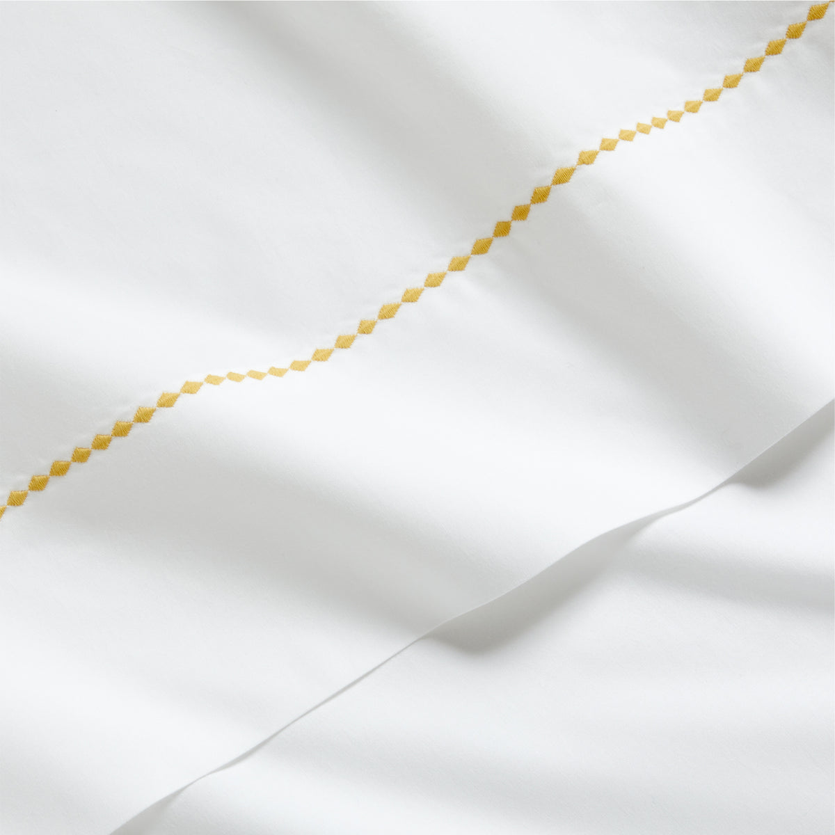 White percale sheet set with a yellow diamond embroidered border.