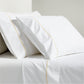 White percale sheet set with yellow diamond embroidered detail on pillowcases and flat sheet.