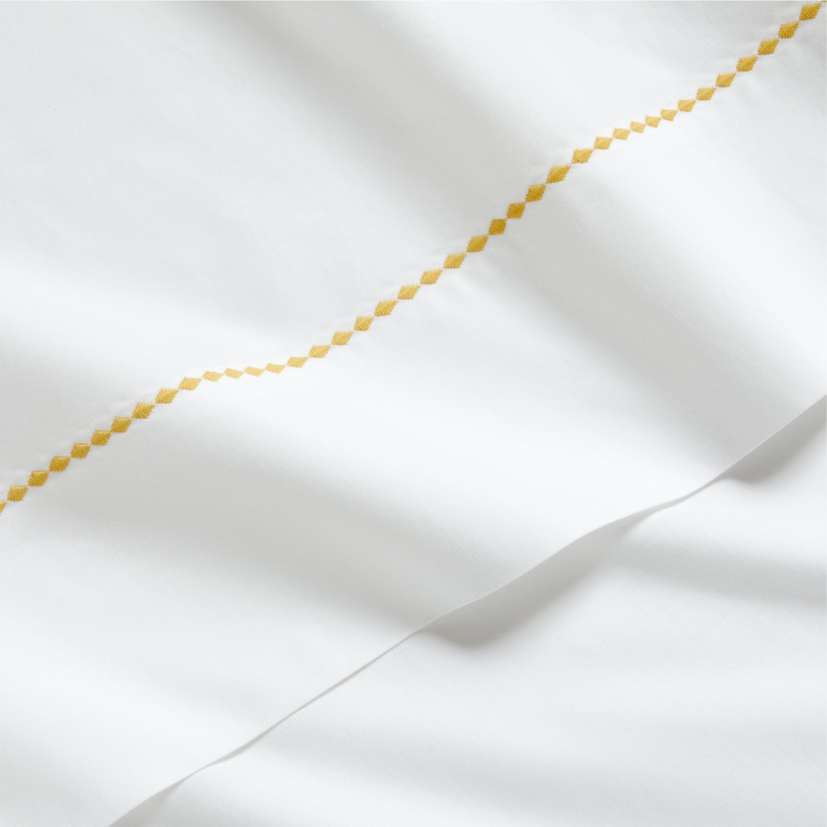 White percale sheet set with a yellow diamond embroidered border.