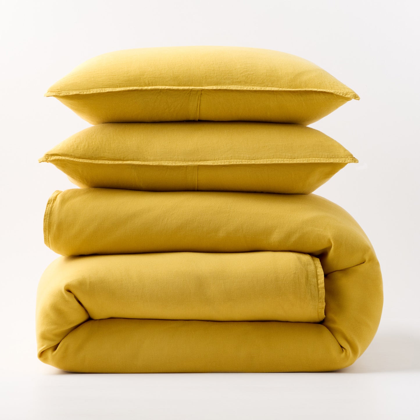 Stacked yellow European washed linen duvet cover and two matching pillow shams on a white background.