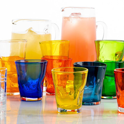 Collection of colorful Henri mouth-blown glassware including yellow, orange, blue, and green glasses and pitchers.