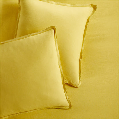Two yellow washed linen pillow shams with 2" flange and double-needle stitching, on a matching linen sheet.