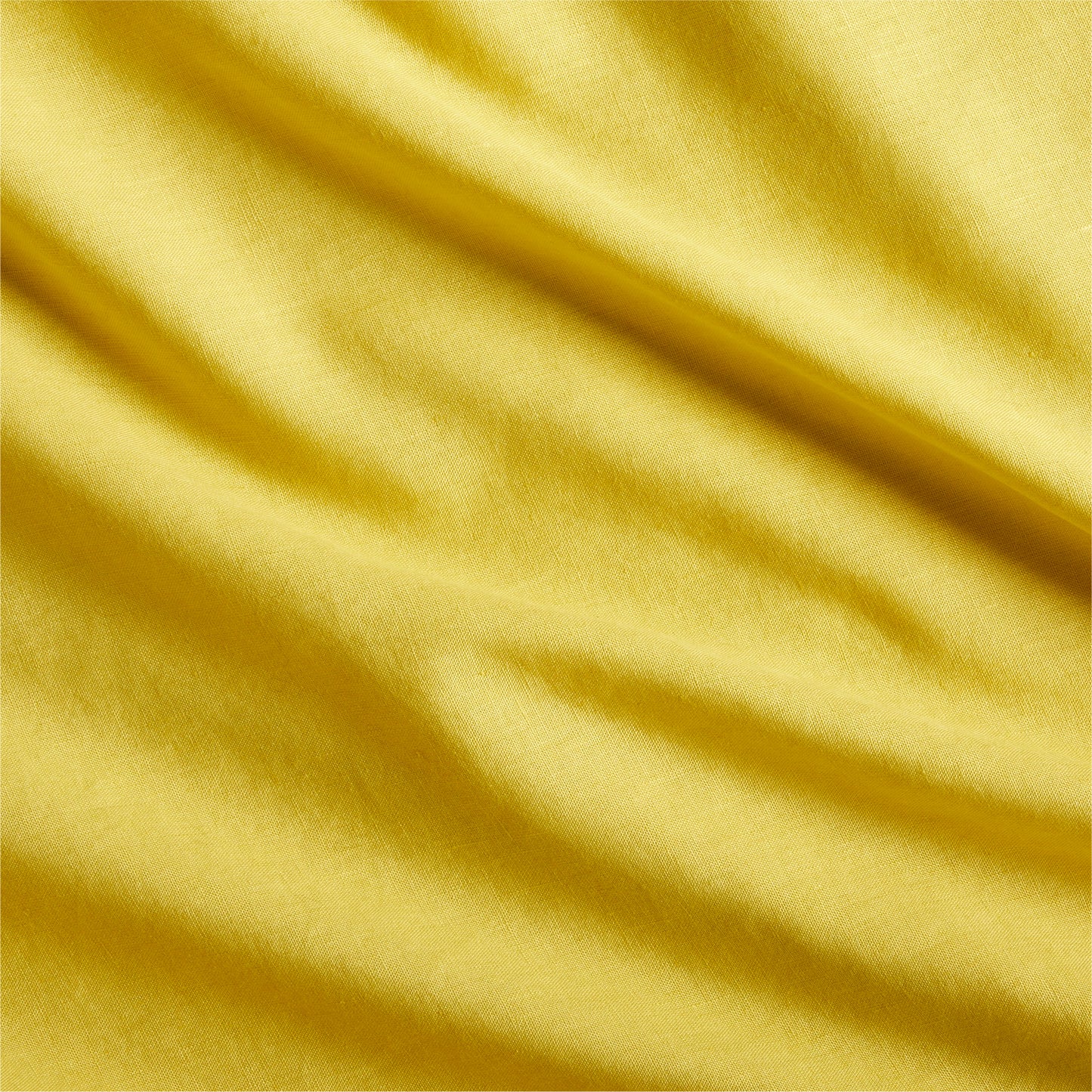 Close-up of a yellow washed linen pillow sham fabric with subtle wrinkles and texture.