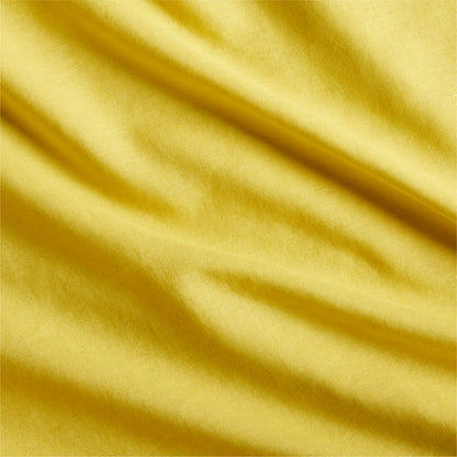 Close-up of a yellow washed linen pillow sham fabric with subtle wrinkles and texture.