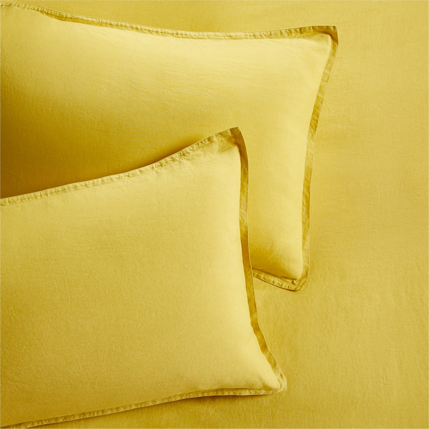 Set of 2 yellow washed Italian linen pillow shams with 2" flange and double-needle stitching.